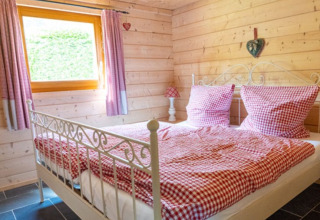 Gezellige slaapkamer met rood geruite dekbedovertrekken bij Natur-Camping Langenwald, glamping Baden-Württemberg.