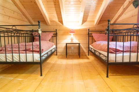 Glamping-indkvartering med to enkeltsenge, ternet sengetøj og træinteriør hos Natur-Camping Langenwald.