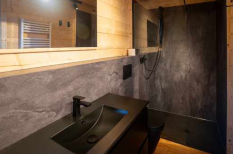 Baño moderno con lavabo negro, ducha y paneles de madera en Natur-Camping Langenwald, Baden-Württemberg.