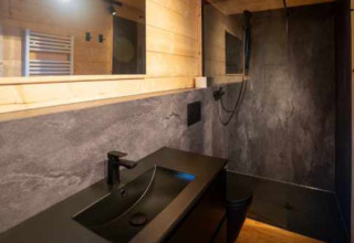 Bagno moderno con lavandino nero, doccia e legno al Natur-Camping Langenwald nel Baden-Württemberg.