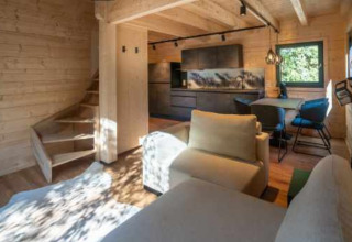 Moderne glampingaccommodatie met houten interieur, salon, eettafel en keuken in Baden-Württemberg.