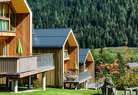 Chalets en bois avec terrasses sur des collines vertes entourées de forêt au glamping HOCHoben - Chalets Oostenrijk.
