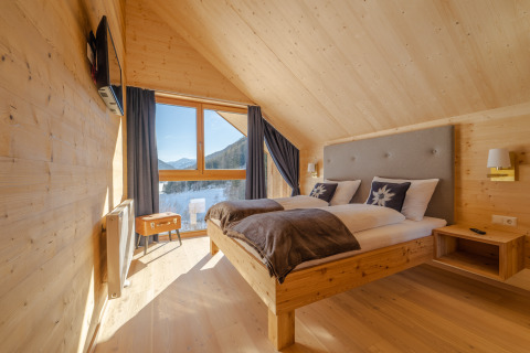 Moderne træsoveværelse i HOCHoben - Chalets Oostenrijk med fjeldudsigt gennem store vinduer.