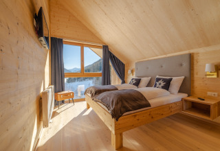 Dormitorio moderno de madera en HOCHoben - Chalets Oostenrijk con vistas panorámicas a las montañas.