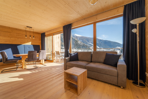Zona soggiorno accogliente presso HOCHoben - Chalets Oostenrijk, con ampie vetrate e vista sulle montagne innevate.