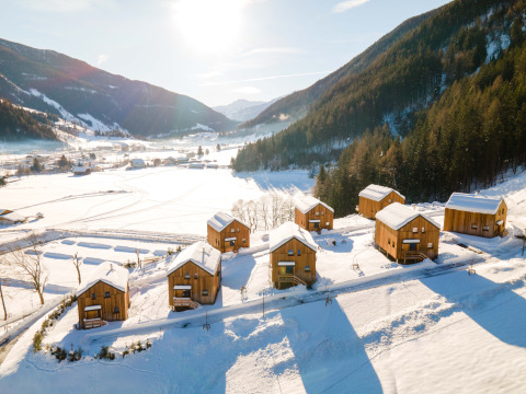 Verschneite Holzhütten bei HOCHoben - Chalets Oostenrijk, idyllisch gelegen in einer verschneiten Berglandschaft.