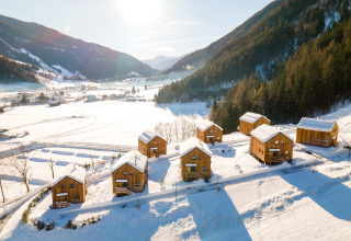 Sneeuwbedekte houten chalets bij HOCHoben - Chalets Oostenrijk, gelegen in een prachtig berglandschap.