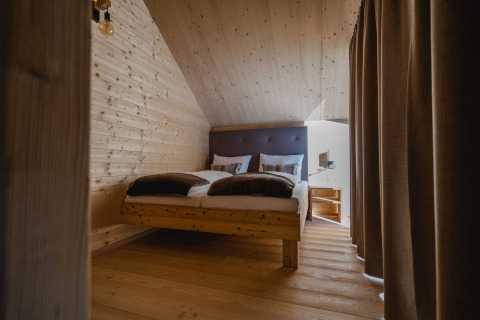 Alojamiento glamping moderno en HOCHoben Chalets Austria con interior de madera y cama cómoda.