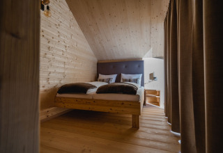 Moderna sistemazione glamping presso HOCHoben Chalets Austria con interno in legno e letto accogliente.