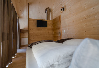 Moderne glampingaccommodatie bij HOCHoben Chalets Oostenrijk met houten muren, bed en televisie.