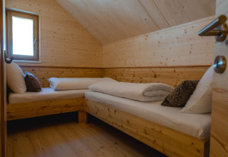 Knusse glampingkamer met twee houten bedden en schuin plafond bij HOCHoben Chalets Oostenrijk.