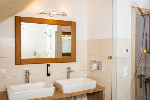Moderne badkamer met dubbele wastafel, grote spiegel en houtaccenten bij HOCHoben - Chalets Oostenrijk glamping.