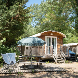 Buiten glampingaccommodatie bij Huttopia Le Moulin - Glamping Ardèche, midden in het groen met terras.