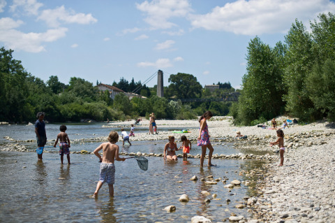 Persone si godono una giornata di sole al fiume presso Huttopia Le Moulin - Glamping Ardèche nella natura.