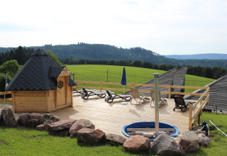 Glamping accommodatie met houten pod, ligstoelen en uitzicht over groene heuvels in het Zwarte Woud.