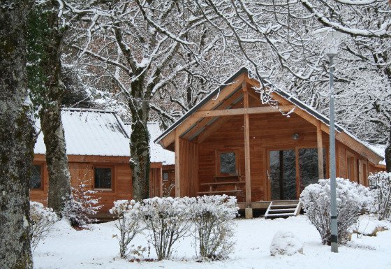 Chalet en bois enneigé à Huttopia Winter Chalets – Divonne Les Bains, glamping dans les Alpes françaises.