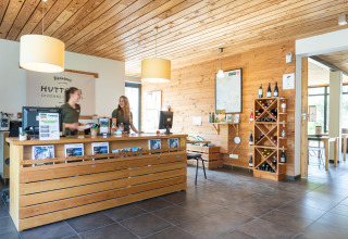 Réception des Huttopia Winter Chalets – Divonne Les Bains avec décor en bois et personnel accueillant pour le glamping.