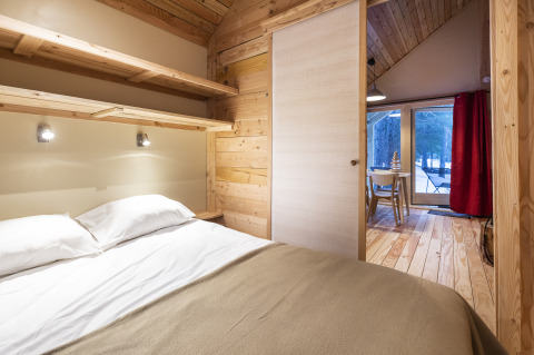 Chambre au décor bois dans Huttopia Winter Chalets, Divonne Les Bains, glamping dans les Alpes françaises.