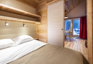 Chambre au décor bois dans Huttopia Winter Chalets, Divonne Les Bains, glamping dans les Alpes françaises.