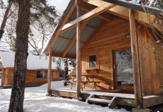 Træhytter dækket af sne i Huttopia Winter Chalets, Divonne Les Bains, glamping i de franske Alper.