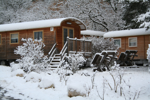 Chalet in legno coperti di neve a Huttopia Winter Chalets, Divonne Les Bains, glamping nelle Alpi francesi.