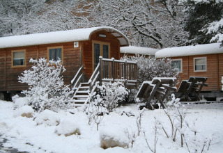 Met sneeuw bedekte houten woningen bij Huttopia Winter Chalets – Divonne Les Bains, glamping in de Franse Alpen.