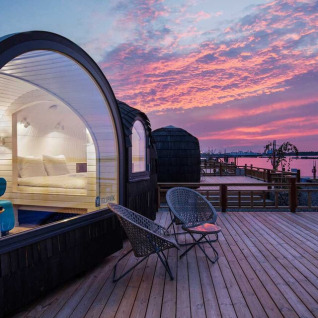 Glamping accommodatie bij Iglu Camp Tangermünde in Saksen-Anhalt, moderne iglohutten aan het water bij zonsondergang.