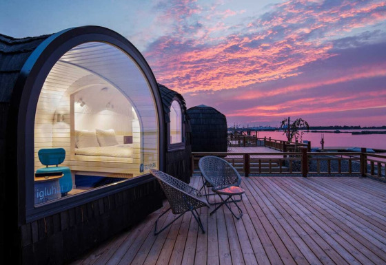 Glamping accommodation by the lake at Iglu Camp Tangermünde, Saxony-Anhalt, with modern igloo huts at sunset.