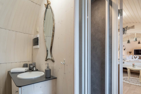 Moderne badkamer bij Iglu Camp Tangermünde glamping met uniek spiegel en zicht op gezellige slaapkamer.