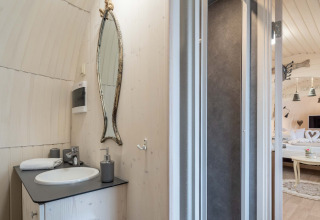 Salle de bain moderne de l'Iglu Camp Tangermünde glamping, avec miroir unique et vue sur la chambre.