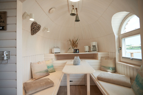 Accogliente interno di igloo glamping a Iglu Camp Tangermünde con panca, tavolo e ampia finestra.
