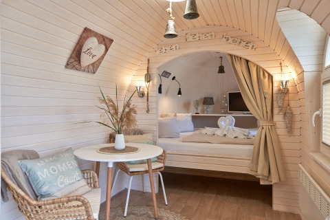 Hébergement glamping douillet à Iglu Camp Tangermünde avec lit confortable, table et décoration chaleureuse.