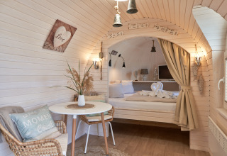 Gemütliche Glamping-Unterkunft bei Iglu Camp Tangermünde mit elegantem Bett, Sitzbereich und Dekor.