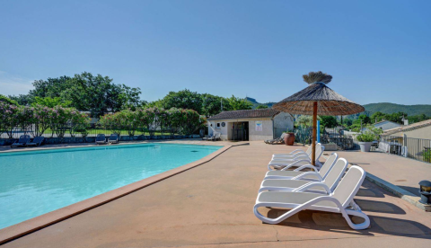 Außenpool mit Sonnenliegen und Strohdachschirmen bei Camping La Chapoulière - Glamping Ardèche.