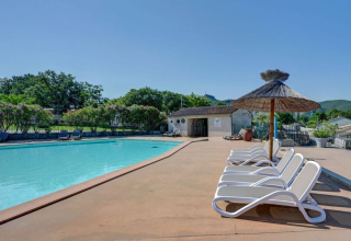 Piscine extérieure avec transats et parasols en paille au Camping La Chapoulière - Glamping Ardèche.