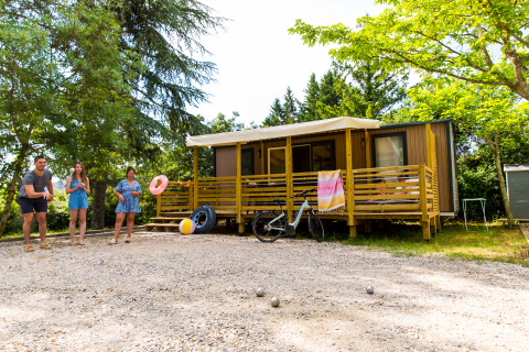 Gezin speelt jeu de boules voor een glamping accommodatie op Camping La Chapoulière in Ardèche, omringd door groen.