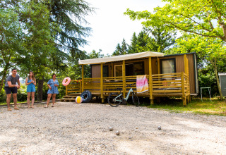 Familia juega petanca frente a un alojamiento glamping en Camping La Chapoulière, Ardèche, rodeados de árboles.