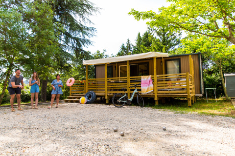 Gezin speelt jeu de boules voor een glamping accommodatie op Camping La Chapoulière in Ardèche, omringd door groen.