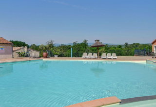 Außenpool mit Liegestühlen und schöner grüner Landschaft im Glampingbereich von Camping La Chapoulière, Ardèche.