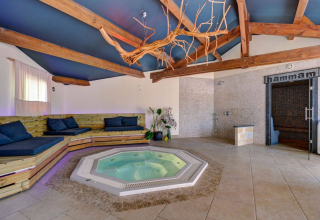 Binnen wellnessruimte met jacuzzi, houten banken en hammam bij Camping La Chapoulière - Glamping Ardèche.