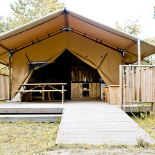 Hébergement glamping au Campingpark Rerik avec grande tente, terrasse en bois et table de pique-nique.