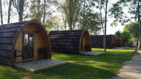 Atractivos alojamientos de glamping en Campingpark Rerik con cabañas de madera rodeadas de naturaleza y árboles.