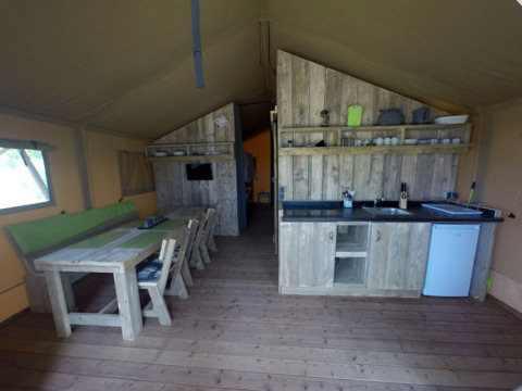 Glamping-Unterkunft im Campingpark Rerik mit Holzmöbeln, Essbereich und Küchenzeile.
