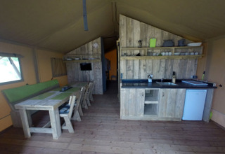 Alojamiento glamping en Campingpark Rerik con muebles rústicos de madera, comedor y pequeña cocina.