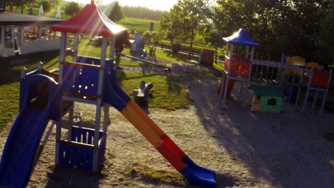 Playground at Campingpark Rerik - Glamping Rerik with slides, climbing frames and sunshine in the background.