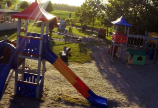 Aire de jeux au Campingpark Rerik - Glamping Rerik avec toboggans et cabanes sous un soleil éclatant.