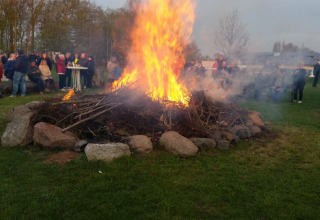 People gather around a large bonfire at Campingpark Rerik - Glamping Rerik, enjoying the outdoor atmosphere.