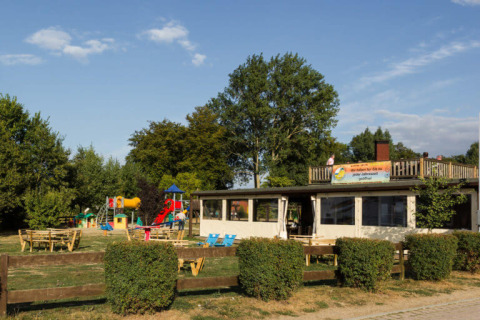 Außenansicht von Campingpark Rerik - Glamping Rerik mit Spielplatz, Sitzbänken und viel Grün.