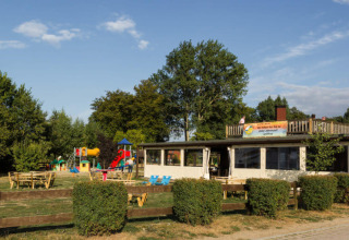Buitenaanzicht van Campingpark Rerik - Glamping Rerik met speeltuin, banken en groene omgeving.