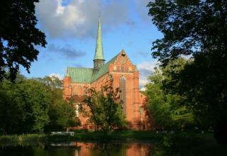Backsteinkirche mit hohem Turm in grüner Umgebung nahe Campingpark Rerik - Glamping Rerik am Teich.